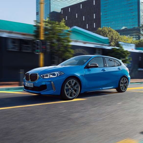 BMW Série 1, perspetiva lateral a três quartos. BMW Série 1 na pintura azul Misano metalizada, perspetiva frontal a três quartos do automóvel em movimento.
