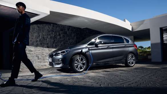 BMW 225xe Active Tourer híbrido plug-in, F45, perspetiva lateral a três quartos, em frente a um edifício BMW 225xe Active Tourer híbrido plug-in, F45, perspetiva lateral a três quartos, em frente a um edifício com um modelo