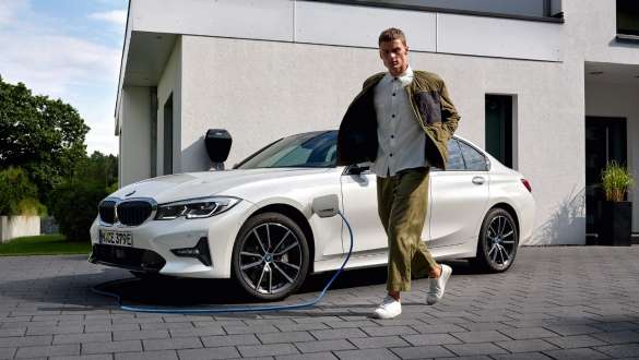 BMW Série 3 Berlina híbrido plug-in, 2021, G20, perspetiva frontal a três quartos, a carregar BMW Série 3 Berlina híbrido plug-in, 2021, G20, perspetiva frontal a três quartos, a carregar com um modelo