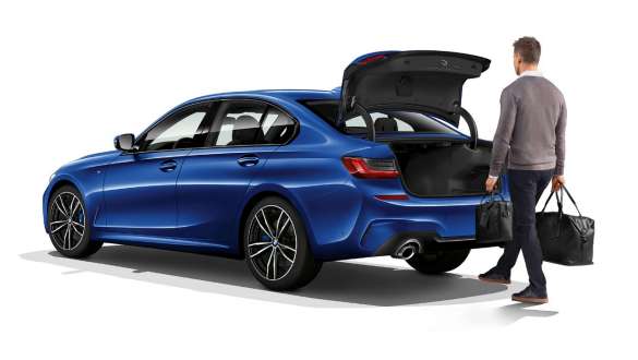 BMW Série 3 Berlina, funcionamento automático da porta da bagageira. Perspetiva traseira a três quartos do BMW Série 3 Berlina parado com o condutor a abrir automaticamente a porta da bagageira com o pé.