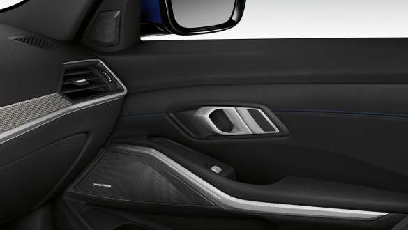 BMW Série 3 Berlina, sistema de som surround Harman Kardon. Grande plano do interior da porta do lado do passageiro da frente iluminada com altifalante integrado e sistema de som surround Harman Kardon.