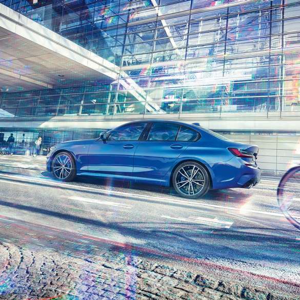 BMW Série 3 Berlina, perspetiva lateral. Perspetiva lateral diurna do BMW Série 3 Berlina parado em frente de um edifício em vidro.