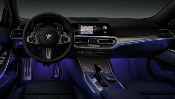 BMW Série 3 Berlina (G20), luz ambiente. Perspetiva frontal do interior do BMW Série 3 Berlina (G20) com espaço para as pernas iluminado a azul pela luz ambiente.