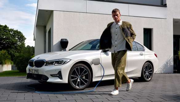 BMW Série 3 Berlina híbrido plug-in, 2021, G20, perspetiva frontal a três quartos, a carregar BMW Série 3 Berlina híbrido plug-in, 2021, G20, perspetiva frontal a três quartos, a carregar com um modelo