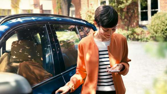 Uma mulher a olhar para o smartphone, BMW Série 5 Berlina, G30 Uma mulher a sair de um BMW e a olhar para o smartphone, BMW Série 5 Berlina, G30