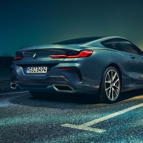 BMW Série 8 Coupé, perspetiva traseira a três quartos. BMW Série 8 Coupé parado num cenário noturno, perspetiva traseira a três quartos.