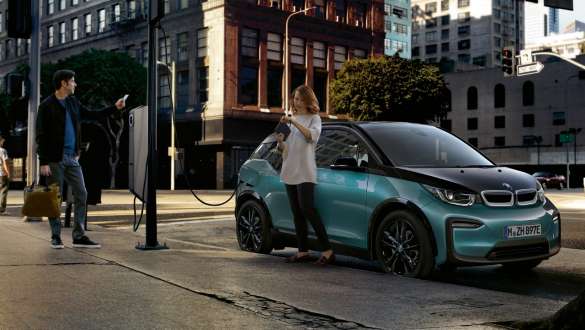 BMW i3 I01 2018 num posto de carregamento público Casal a carregar o seu BMW i3 num posto de carregamento público, I01 2018, pintura azul Ridge Mountain com realce em cinza Frozen metalizada