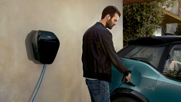 Homem a carregar o seu BMW i3 I01 2018 com uma BMW Wallbox Homem com cabo de carregamento de ligação à BMW Wallbox, BMW i3 I01 2018, pintura azul Ridge Mountain com realce em cinza Frozen metalizada