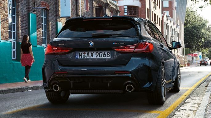 BMW M135i xDrive, perspetiva traseira. BMW M135i xDrive na pintura preto Sapphire metalizada, a estacionar, perspetiva traseira.