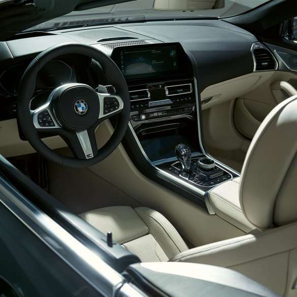 BMW M850i xDrive Cabrio, cockpit. BMW M850i xDrive Cabrio em cinza Dravit metalizada com capota flexível aberta, posto de condução com volante M em pele.