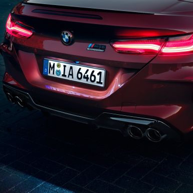 BMW M8 Competition Cabrio, grande plano da traseira. BMW M8 Competition Cabrio na pintura vermelho Motegi metalizada, grande plano da traseira com faróis traseiros LED e logótipo M8 Competiton.