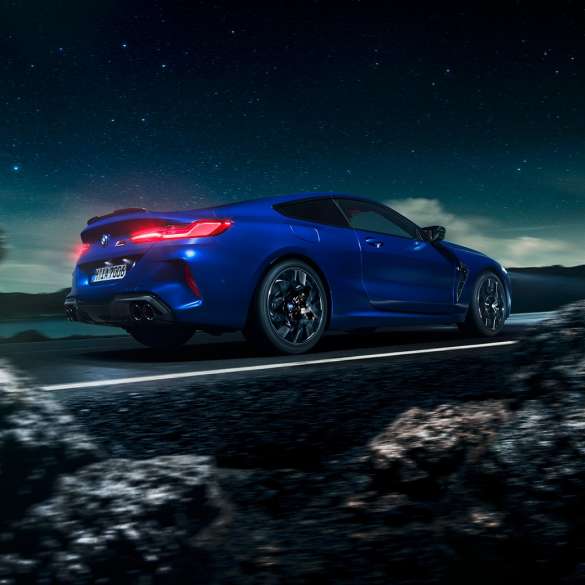 BMW M8 Competition Coupé, perspetiva lateral a três quartos. BMW M8 Competition Coupé na pintura azul Marina Bay metalizada, em movimento sob um céu estrelado, perspetiva lateral a três quartos.