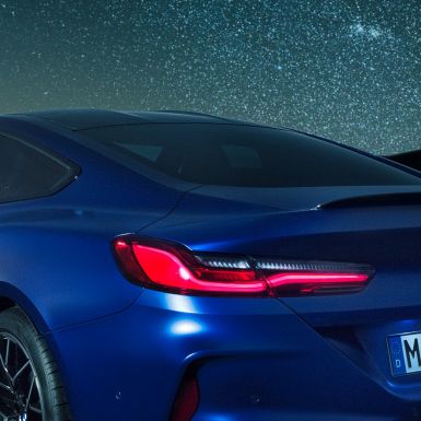 Spoiler traseiro M BMW M8 Competition Coupé na pintura azul Marina Bay metalizada, grande plano das linhas com spoiler traseiro M em carbono à noite.