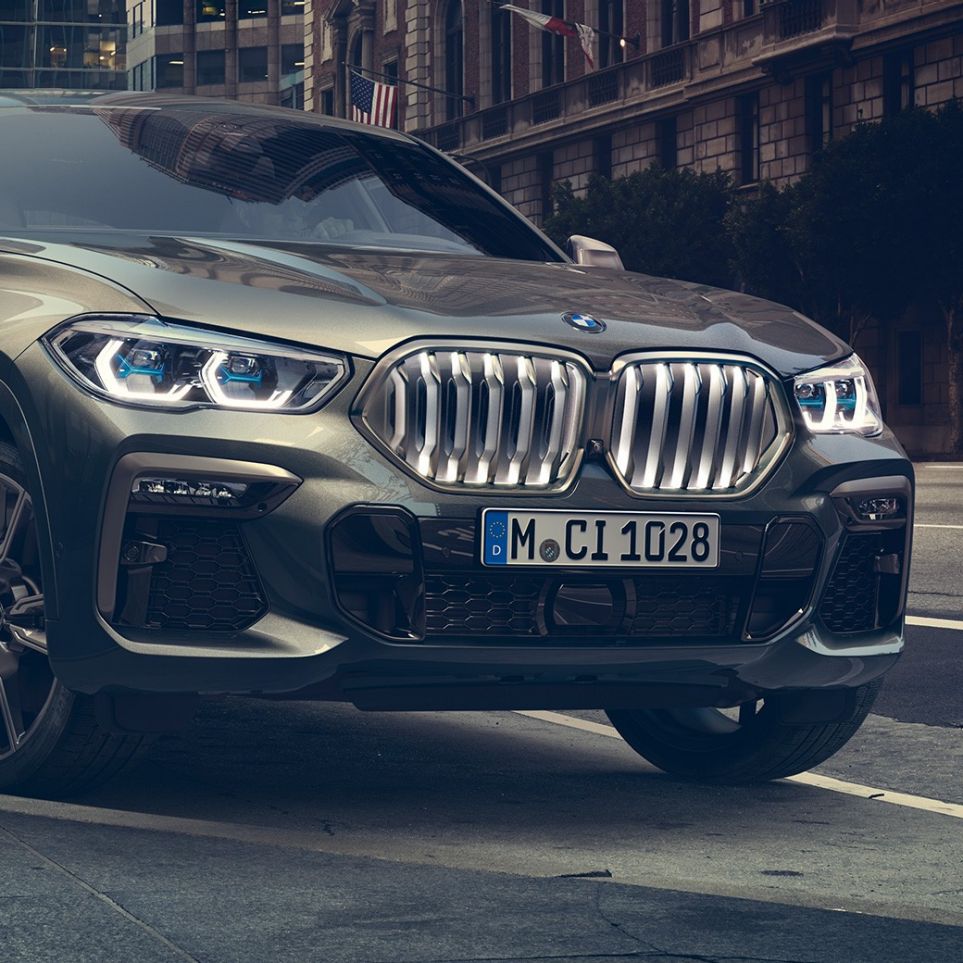 BMW X6 M50i parado BMW X6 M50i, perspetiva frontal a três quartos em frente a um cenário urbano