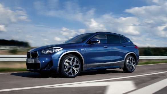 BMW X2 xDrive25e híbrido plug-in, F39, perspetiva lateral a três quartos, em movimento BMW X2 xDrive25e híbrido plug-in, F39, perspetiva lateral a três quartos, em movimento na rua