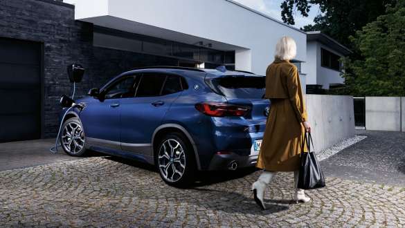 BMW X2 xDrive25e híbrido plug-in, F39, perspetiva traseira a três quartos, a carregar BMW X2 xDrive25e híbrido plug-in, F39, perspetiva traseira, a carregar com modelo