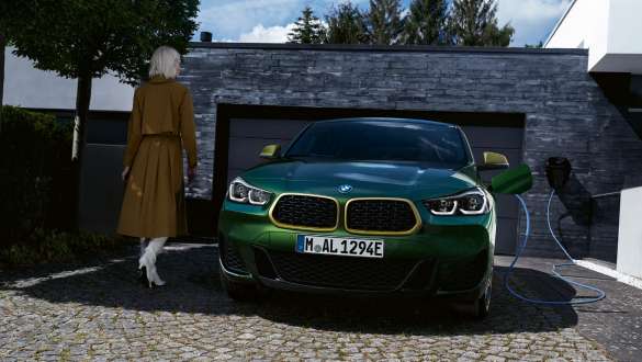 BMW X2 xDrive25e híbrido plug-in, F39, perspetiva frontal, em frente a uma garagem BMW X2 xDrive25e híbrido plug-in, F39, perspetiva frontal, em frente a uma garagem com modelo