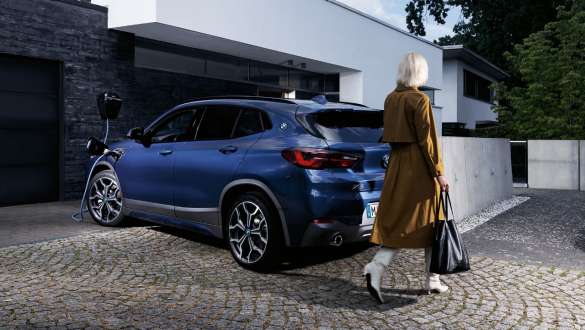 BMW X2 xDrive25e híbrido plug-in, F39, perspetiva traseira a três quartos, a carregar BMW X2 xDrive25e híbrido plug-in, F39, perspetiva traseira, a carregar com modelo