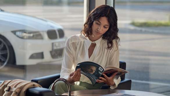 Garantia do Concessionário BMW, BMW Repair & Care Garantia do Concessionário BMW, BMW Repair & Care, mulher sentada com um catálogo BMW na mão