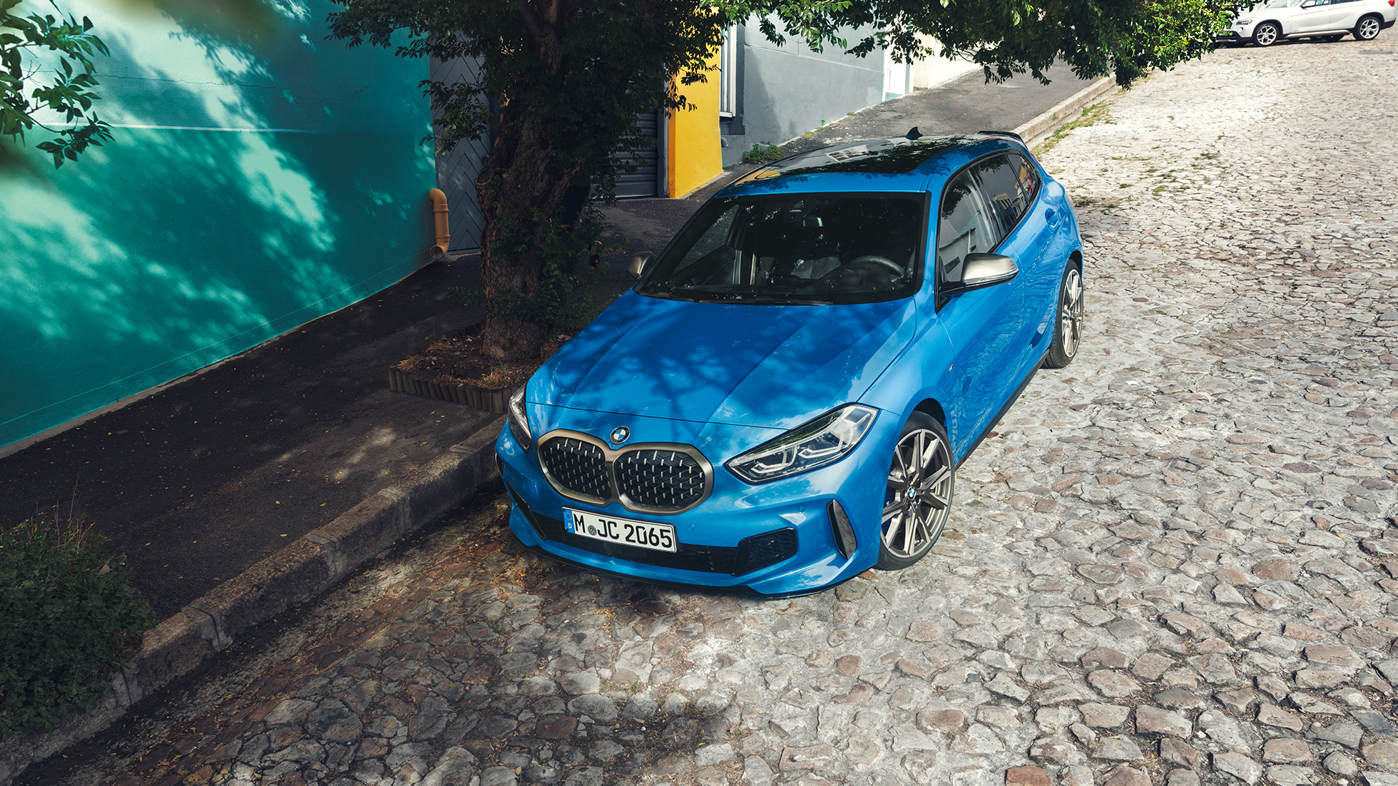 BMW Série 1 na berma da estrada. BMW Série 1 na pintura azul Misano metalizada a estacionar na berma da estrada, perspetiva frontal de topo a três quartos.