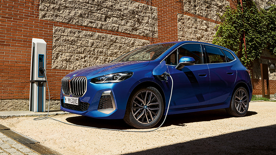 BMW Série 2 Active Tourer híbrido plug-in, U06, 2021, num posto de carregamento BMW Série 2 Active Tourer 230e híbrido plug-in, U06, 2021, pintura azul Portimao M metalizada, perspetiva lateral, num posto de carregamento