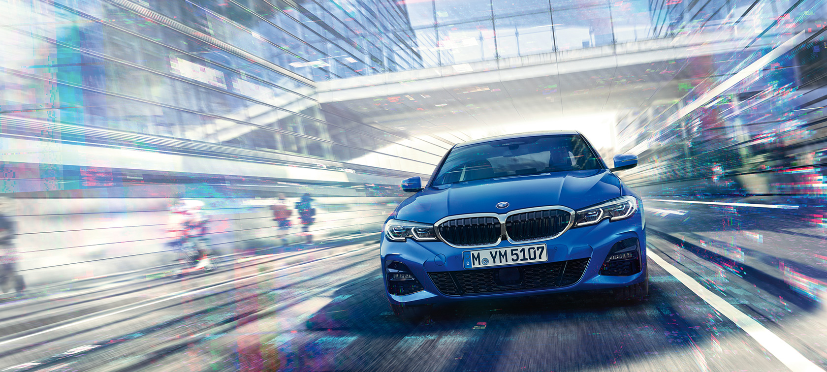 BMW Série 3 Berlina, vista frontal. Vista frontal do BMW Série 3 Berlina durante a condução diurna junto a um edifício em vidro.