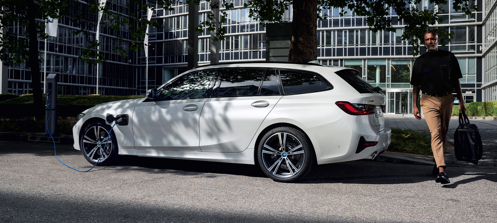 BMW Série 3 Touring híbrido plug-in, 2021, G21, perspetiva lateral a três quartos, a carregar BMW Série 3 Touring híbrido plug-in, 2021, G21, perspetiva lateral a três quartos, a carregar com um modelo
