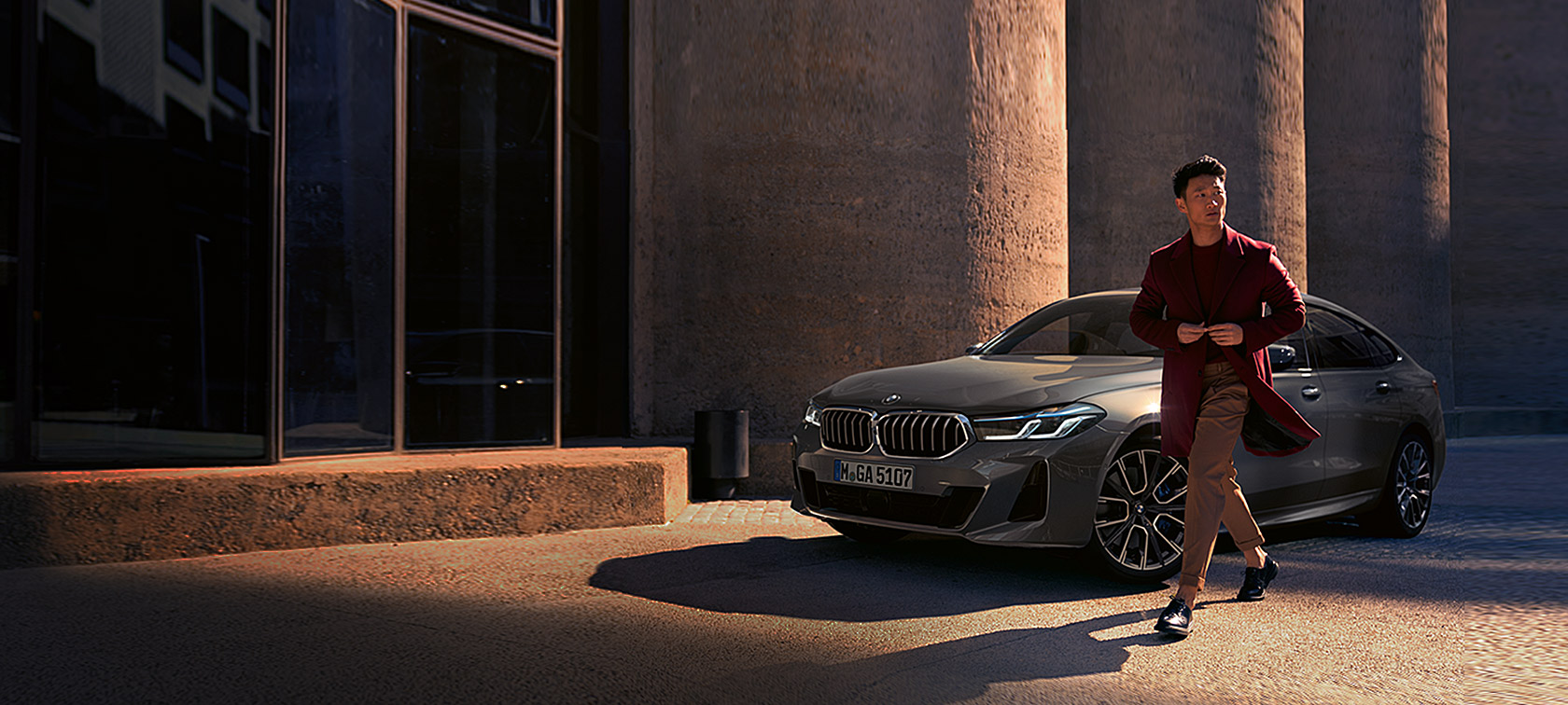BMW Série 6 Gran Turismo, BMW 640i xDrive, G32, 2020, pintura cinza Bernina, homem em frente ao BMW, perspetiva frontal a três quartos, veículo parado