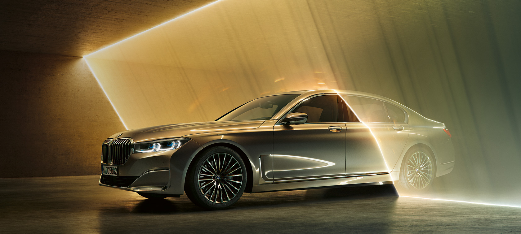 BMW Série 7 Berlina em perspetiva frontal a três quartos BMW Série 7 Berlina: perspetiva frontal a três quartos de um BMW em cinza, rodeado por feixes de luz