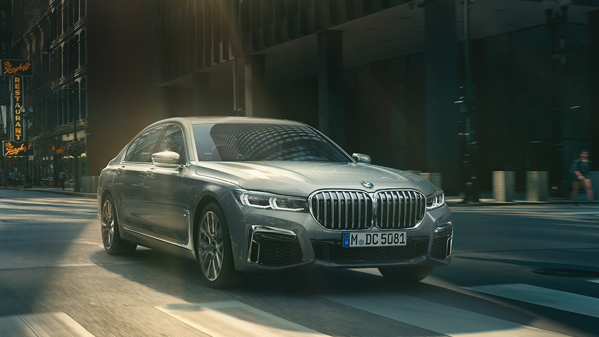Assistente de condução Professional do BMW Série 7 Berlina Assistente de condução Professional: perspetiva frontal a três quartos do BMW Série 7 Berlina em movimento, em frente a um cenário urbano