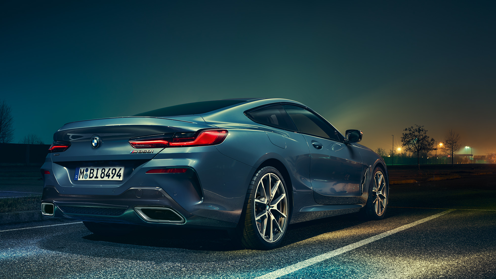BMW Série 8 Coupé, perspetiva traseira a três quartos. BMW Série 8 Coupé parado num cenário noturno, perspetiva traseira a três quartos.