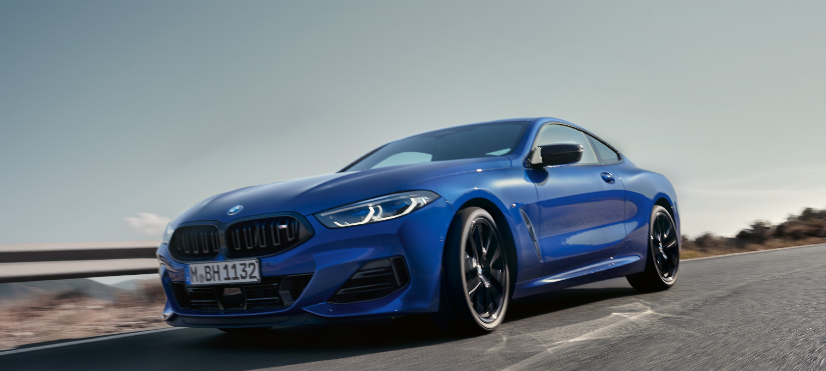 BMW Série 8 Coupé, G15, LCI, atualização, 2022, BMW M850i xDrive, pintura azul Portimao M metalizada, perspetiva frontal, ângulo inferior BMW Série 8 Coupé, G15, LCI, atualização, 2022, BMW M850i xDrive, pintura azul Portimao M metalizada, perspetiva frontal, ângulo inferior, em movimento numa estrada secundária num cenário com encostas