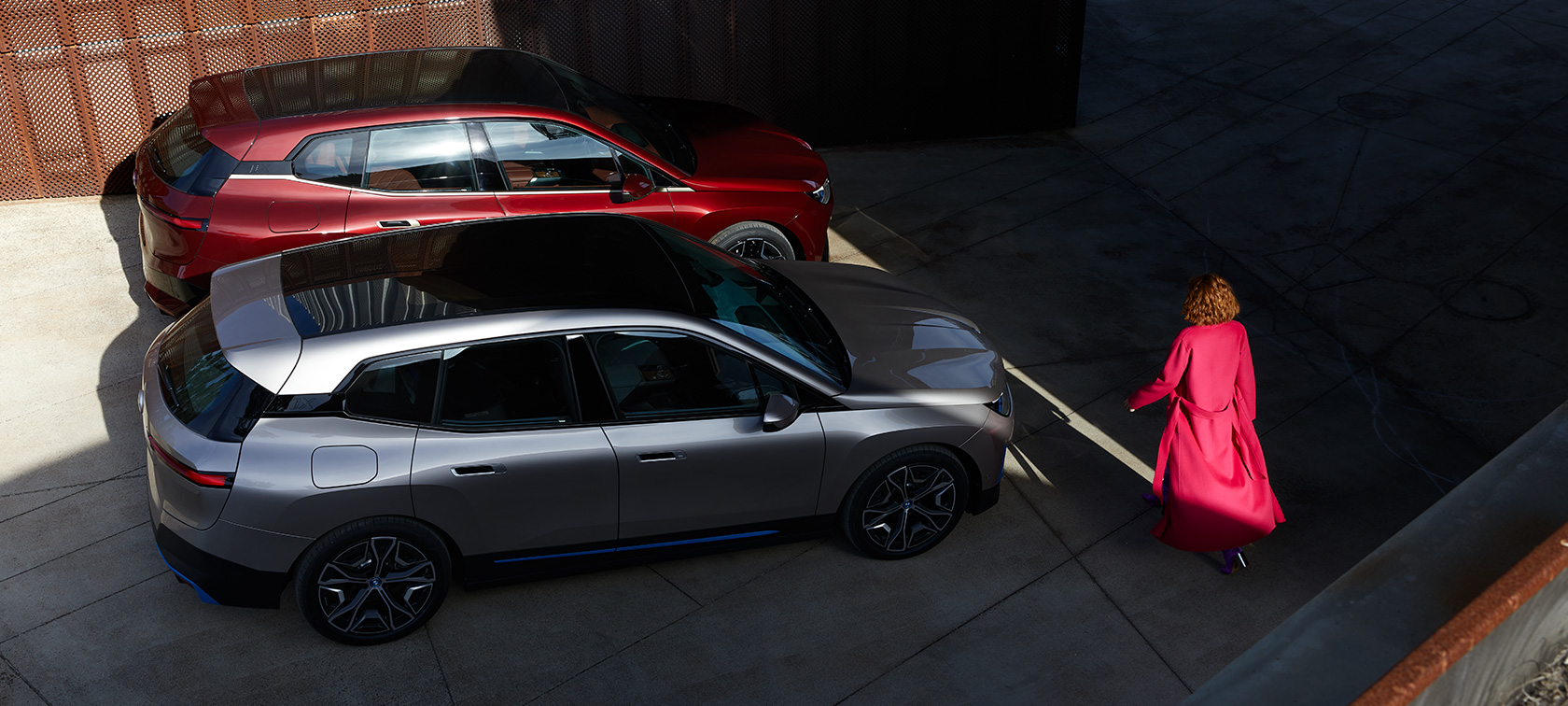 BMW iX, vista aérea, com um modelo BMW iX na cor exterior vermelho Aventurin e na cor exterior prata Cashmere, i20, vista aérea, com um modelo
