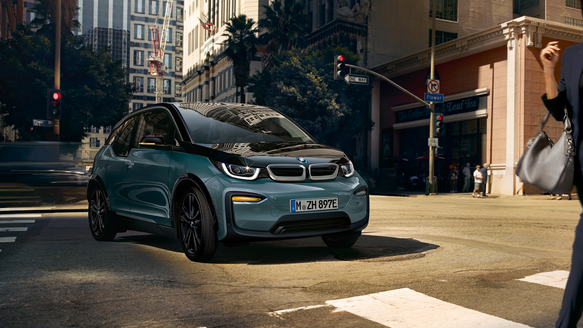 BMW i3 2018 em movimento, perspetiva frontal a três quartos BMW i3 I01 2018 bege Jucaro com realce em cinza Frozen metalizado em movimento num cenário urbano, perspetiva frontal a três quartos