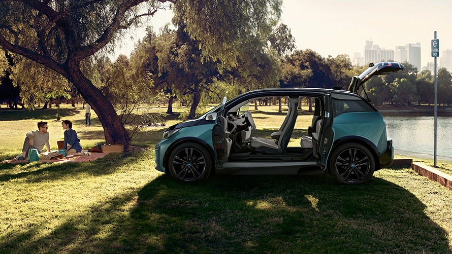BMW i3 2018 num parque de estacionamento BMW i3 I01 2018 bege Jucaro com realce em cinza Frozen metalizado com as portas abertas num parque de estacionamento, perspetiva lateral