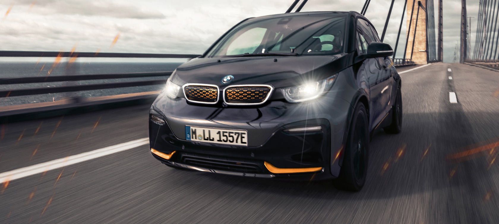 BMW i3, Edição Unique Forever, I01, perspetiva frontal a três quartos BMW i3, Edição Unique Forever, I01, pintura Storm Bay com realce em E-Copper Frozen metalizada, perspetiva frontal a três quartos, em movimento numa autoestrada