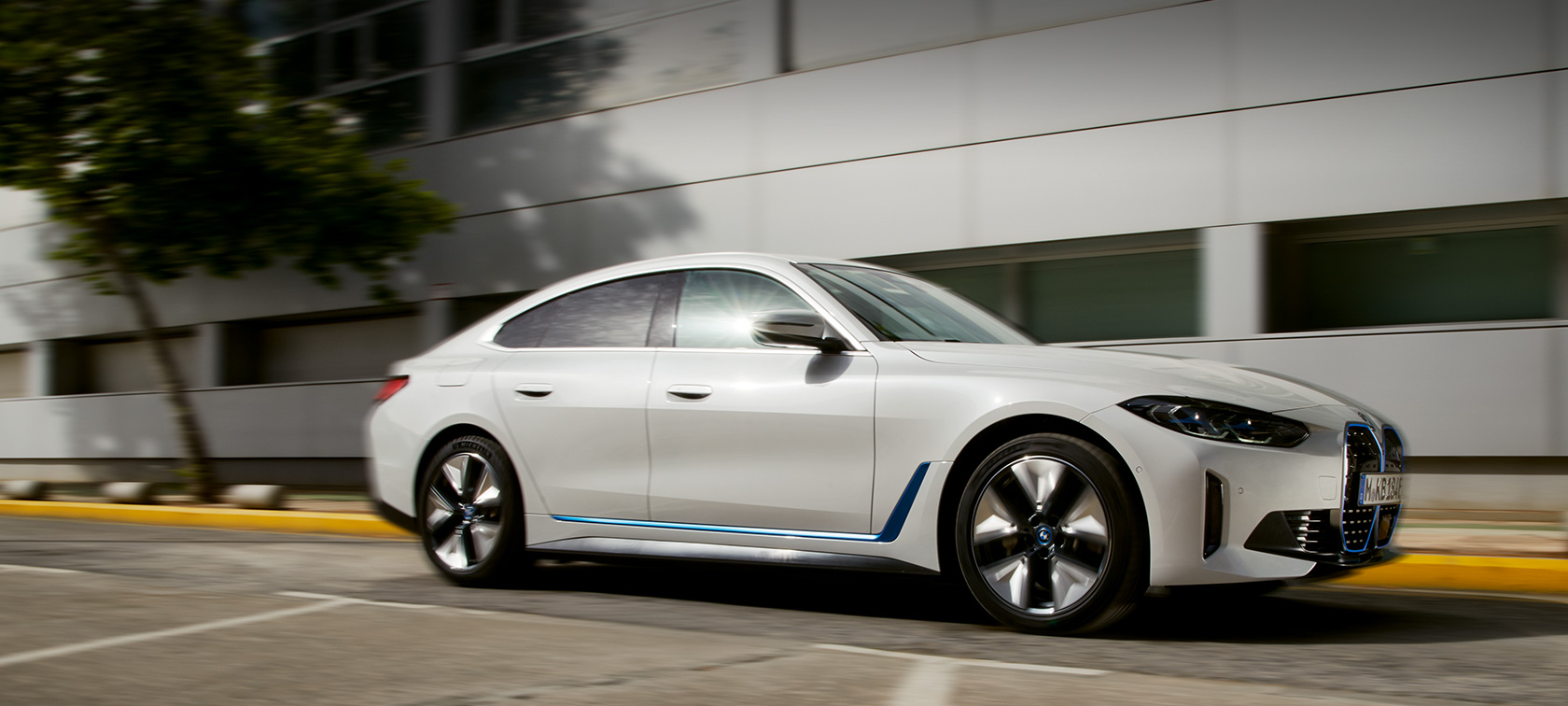 BMW i4 eDrive, G26, 2021, perspetiva lateral a três quartos, em movimento em frente a um edifício BMW i4 eDrive, G26, 2021, perspetiva lateral a três quartos, em movimento em frente a um edifício
