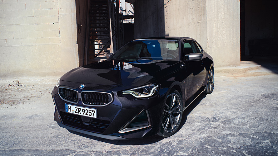 BMW M240i xDrive, G42, 2021, pintura preto Sapphire metalizada, perspetiva frontal a três quartos, parado em frente a um armazém