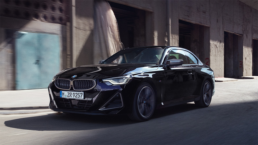 BMW M240i xDrive, G42, 2021, pintura preto Sapphire metalizada, perspetiva lateral a três quartos, parado em frente a armazéns