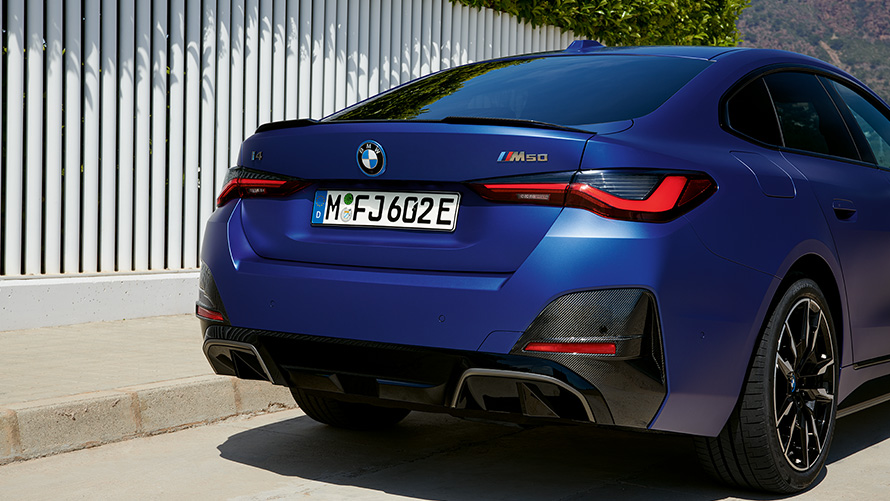 BMW i4 M50, G26, 2021, pintura azul Frozen Portimao BMW Individual metalizada, perspetiva traseira a três quartos, parado junto a uma vedação branca