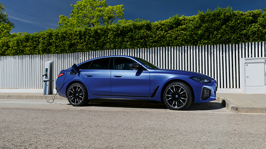 BMW i4 M50, G26, 2021, pintura azul Frozen Portimao BMW Individual metalizada, perspetiva lateral conectado a um posto de carregamento