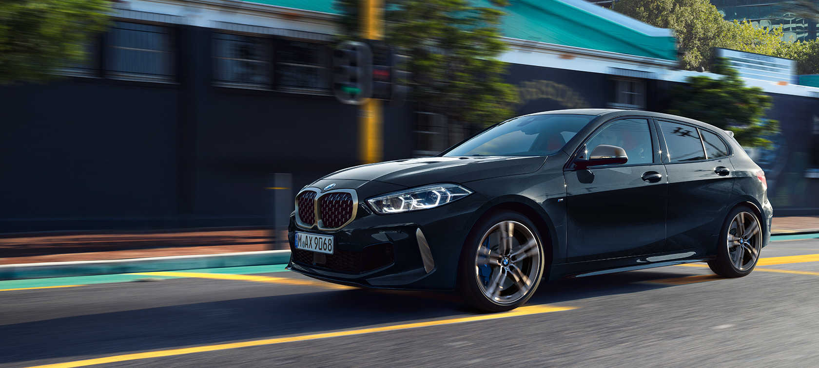 Novo BMW M135i xDrive Novo BMW M135i xDrive na pintura preto Sapphire metalizada, em movimento, perspetiva lateral a três quartos.
