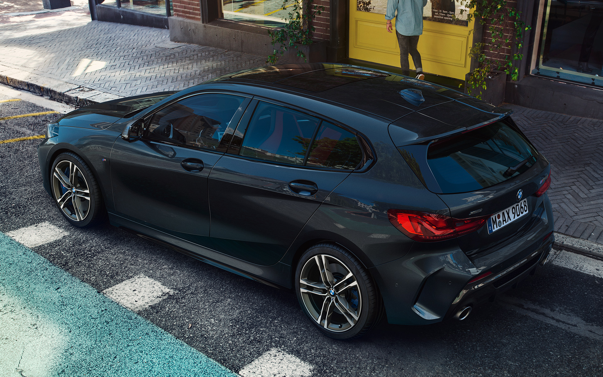 BMW M135i xDrive (F40) em preto Sapphire metalizada a estacionar, perspetiva aérea da lateral