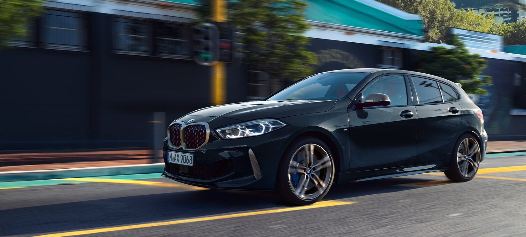 BMW Série 1 M135i xDrive (F40) em preto Sapphire metalizada, em movimento num ambiente urbano