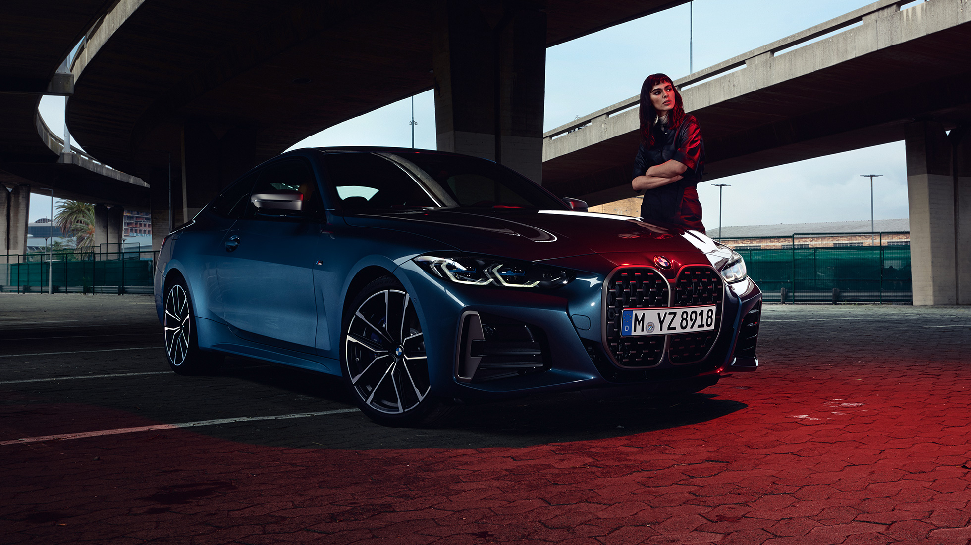 Um modelo ao lado do BMW M440i xDrive Coupé, G22, 2020, perspetiva lateral a três quartos BMW M440i xDrive Coupé, pintura azul Arctic Race metalizada, G22, 2020, perspetiva lateral a três quartos com um modelo