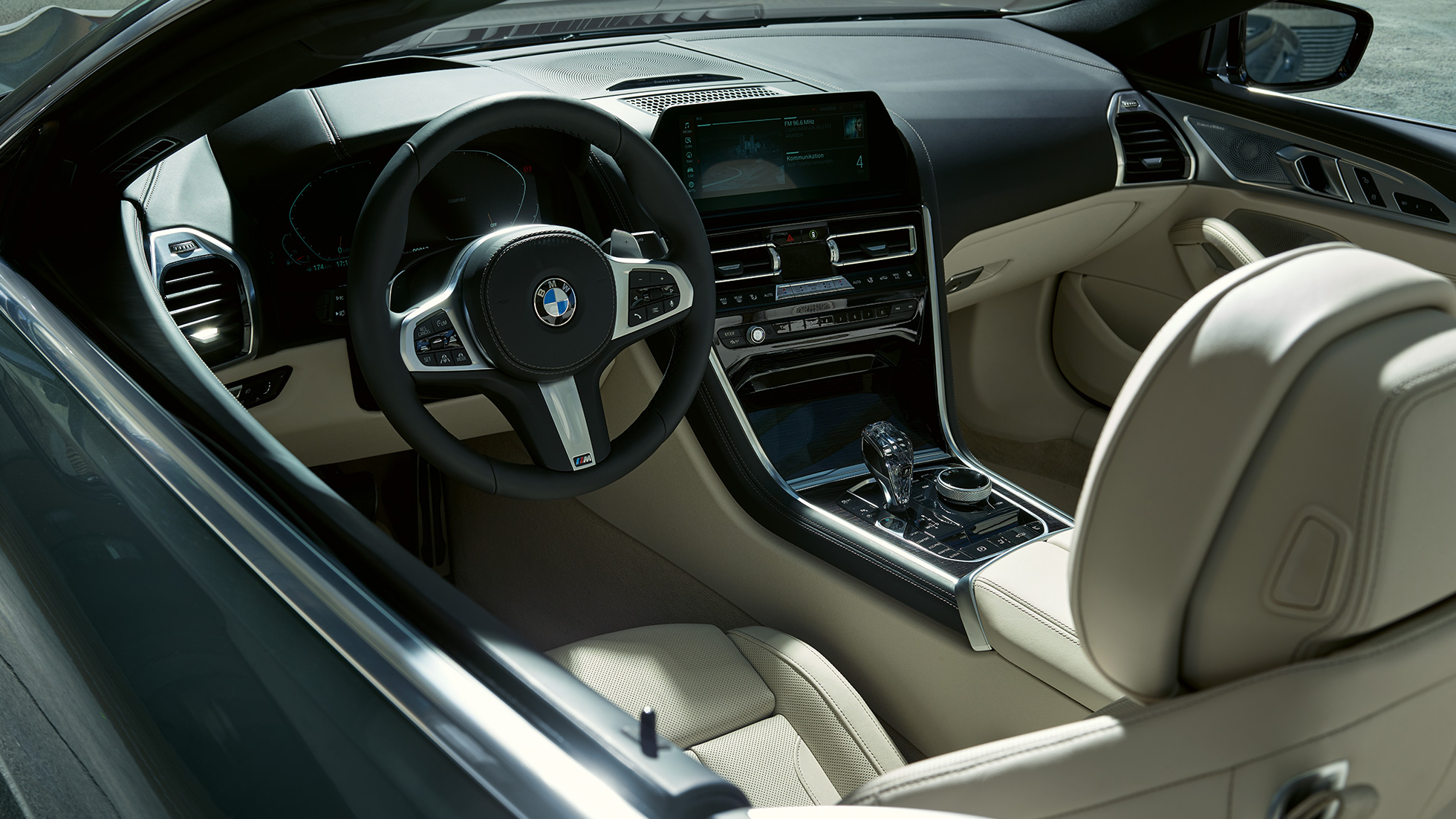 BMW M850i xDrive Cabrio, cockpit. BMW M850i xDrive Cabrio em cinza Dravit metalizada com capota flexível aberta, posto de condução com volante M em pele.