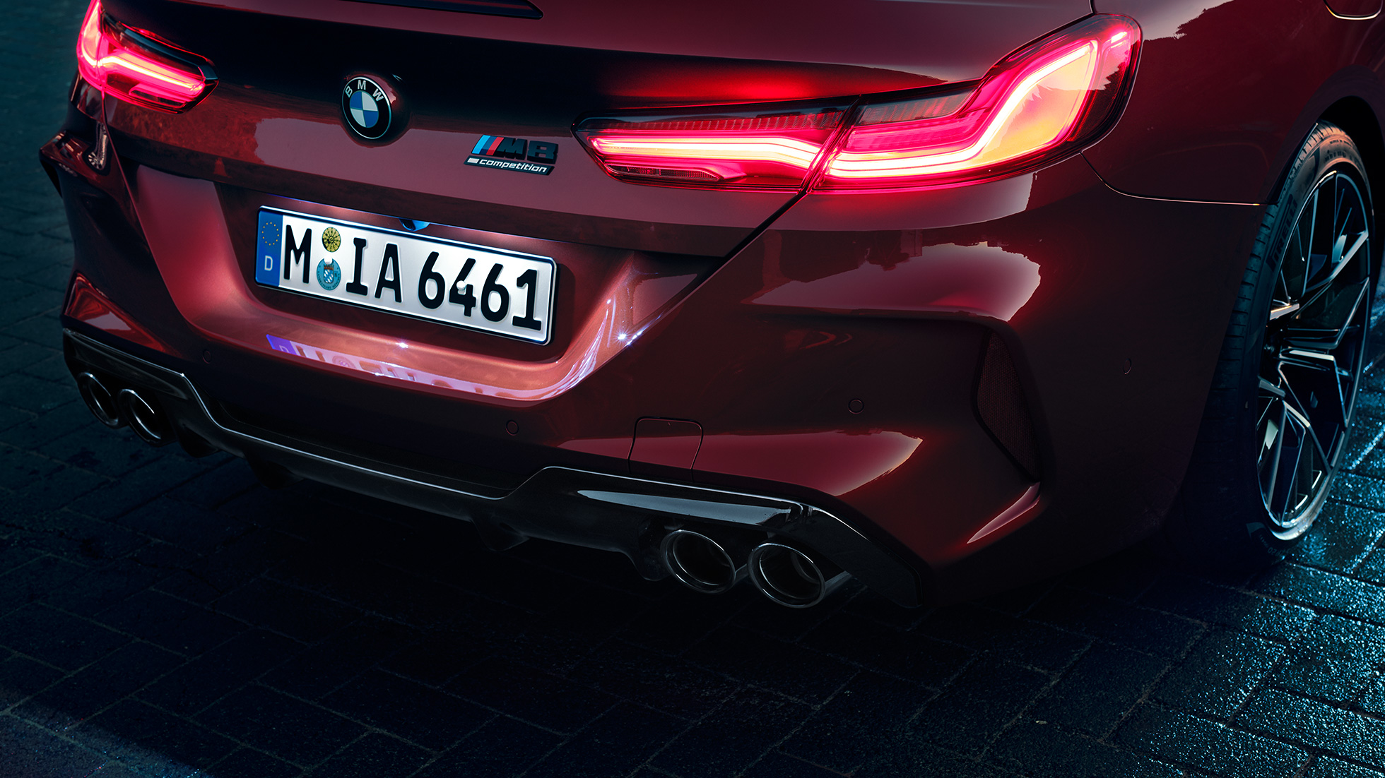 BMW M8 Competition Cabrio, grande plano da traseira. BMW M8 Competition Cabrio na pintura vermelho Motegi metalizada, grande plano da traseira com faróis traseiros LED e logótipo M8 Competiton.