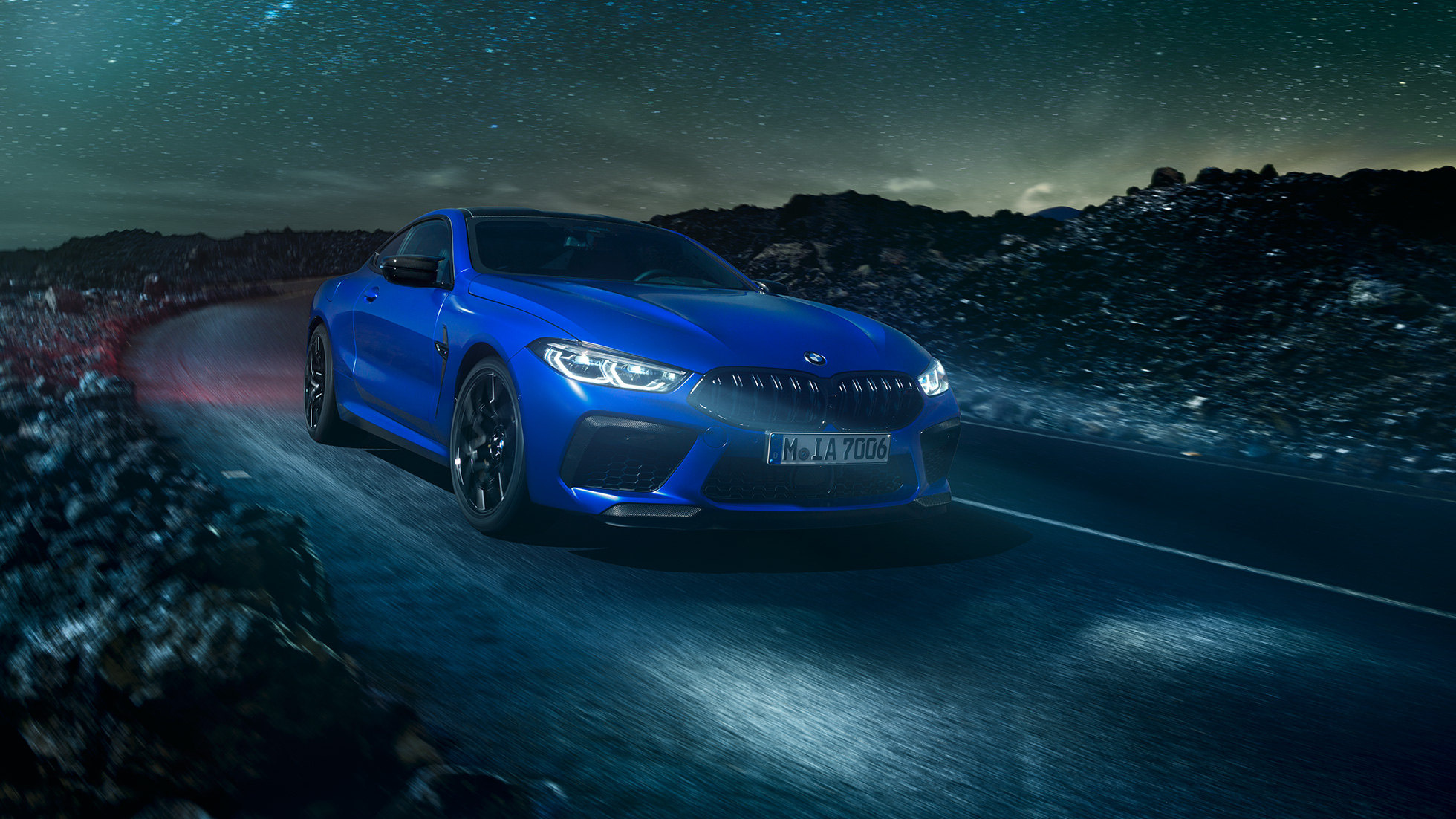 BMW M8 Competition Coupé, perspetiva lateral. BMW M8 Competition Coupé na pintura azul Marina Bay metalizada, parado frente ao deserto, num cenário de lua cheia, perspetiva lateral.