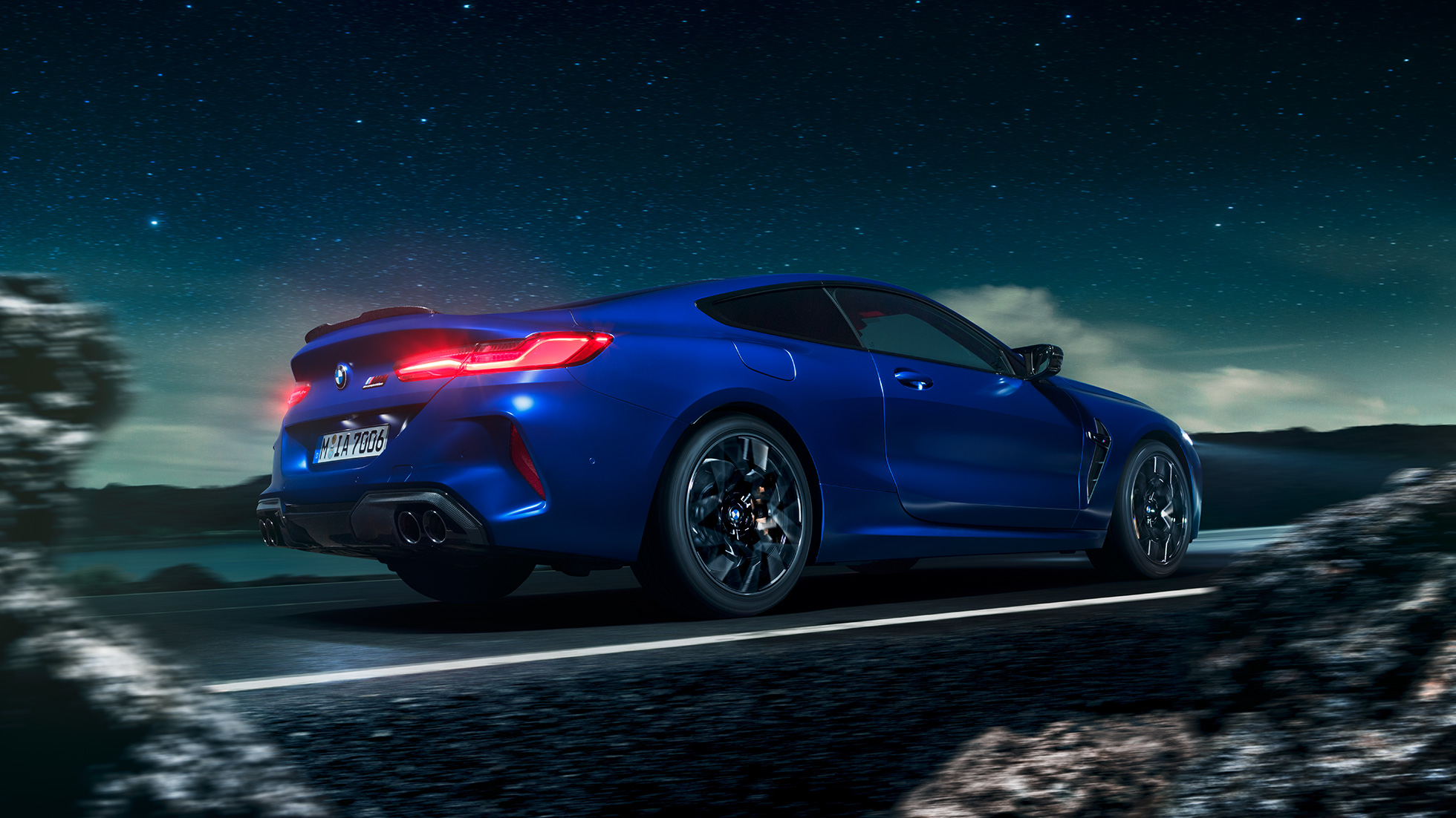 BMW M8 Competition Coupé, perspetiva lateral a três quartos. BMW M8 Competition Coupé na pintura azul Marina Bay metalizada, em movimento sob um céu estrelado, perspetiva lateral a três quartos.