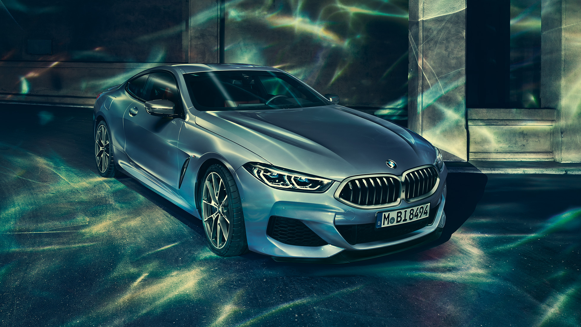 BMW M850i xDrive Coupé, perspetiva frontal esquerda a três quartos. BMW M850i xDrive Coupé na pintura azul Barcelona metalizada, parado em frente a um edifício, perspetiva frontal esquerda a três quartos.